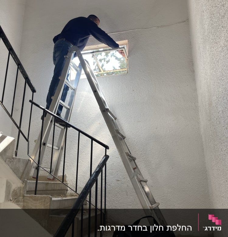 אדם על סולם מתקין זכוכית בחלון קטן